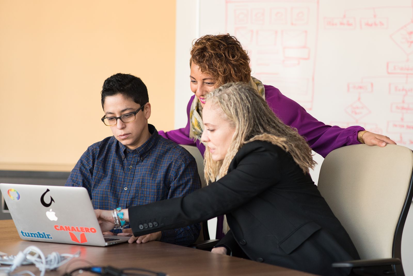 Three DevOps engineers collaborating on a laptop in a modern tech office